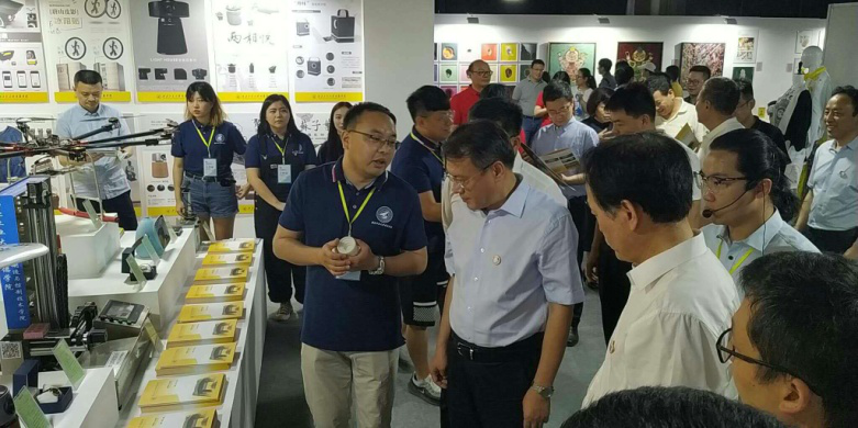 西安市委常委、副市长高杲在青博会听取明德学院师生讲解设计作品